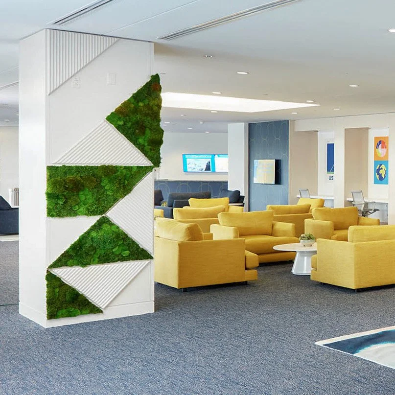 Modern airport lounge with yellow seating, blue and white decor, and a moss wall art piece.