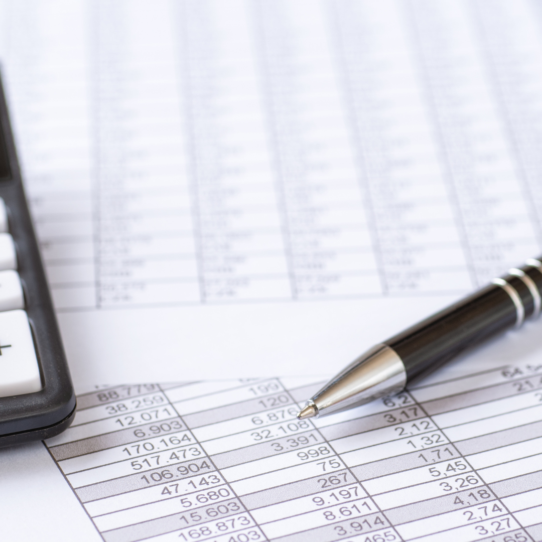 Close-up of financial documents with numerical data, a calculator, and a pen on top of the papers.