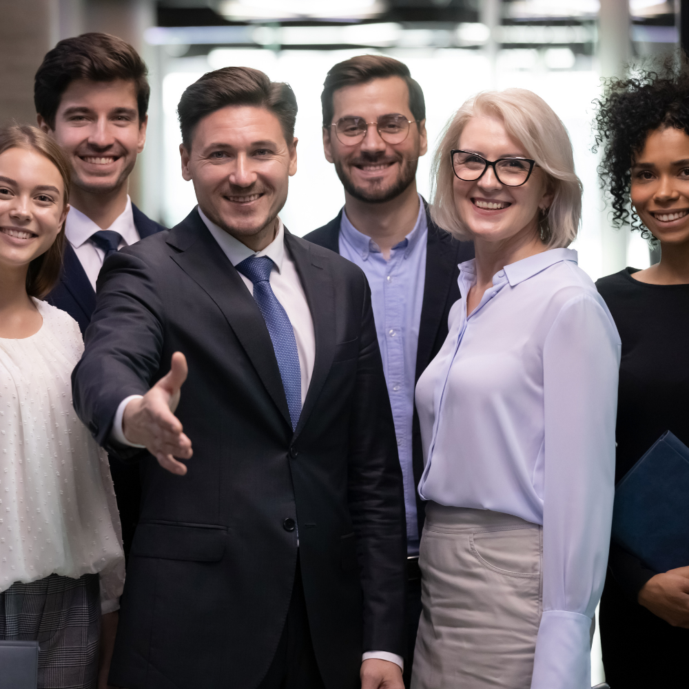 Group of six diverse professionals smiling and posing together in an office conference room.