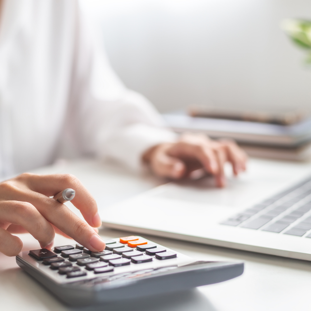 Person using calculator and laptop at a desk