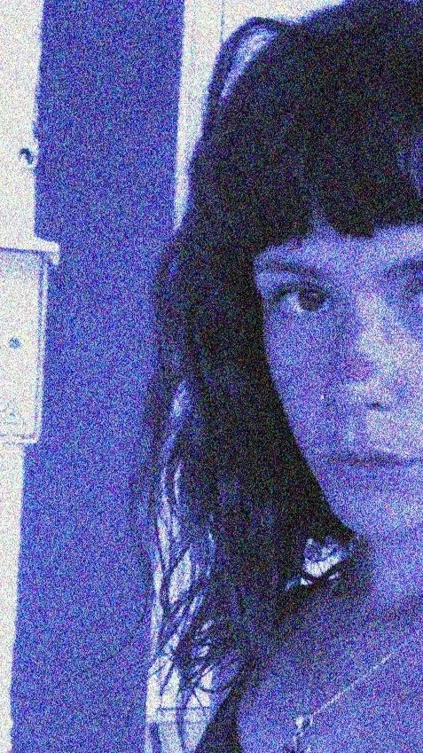 Retrato de una joven con cabello rizado y oscuro, con expresión de sorpresa o asombro, en un entorno con paredes de color púrpura o azul.