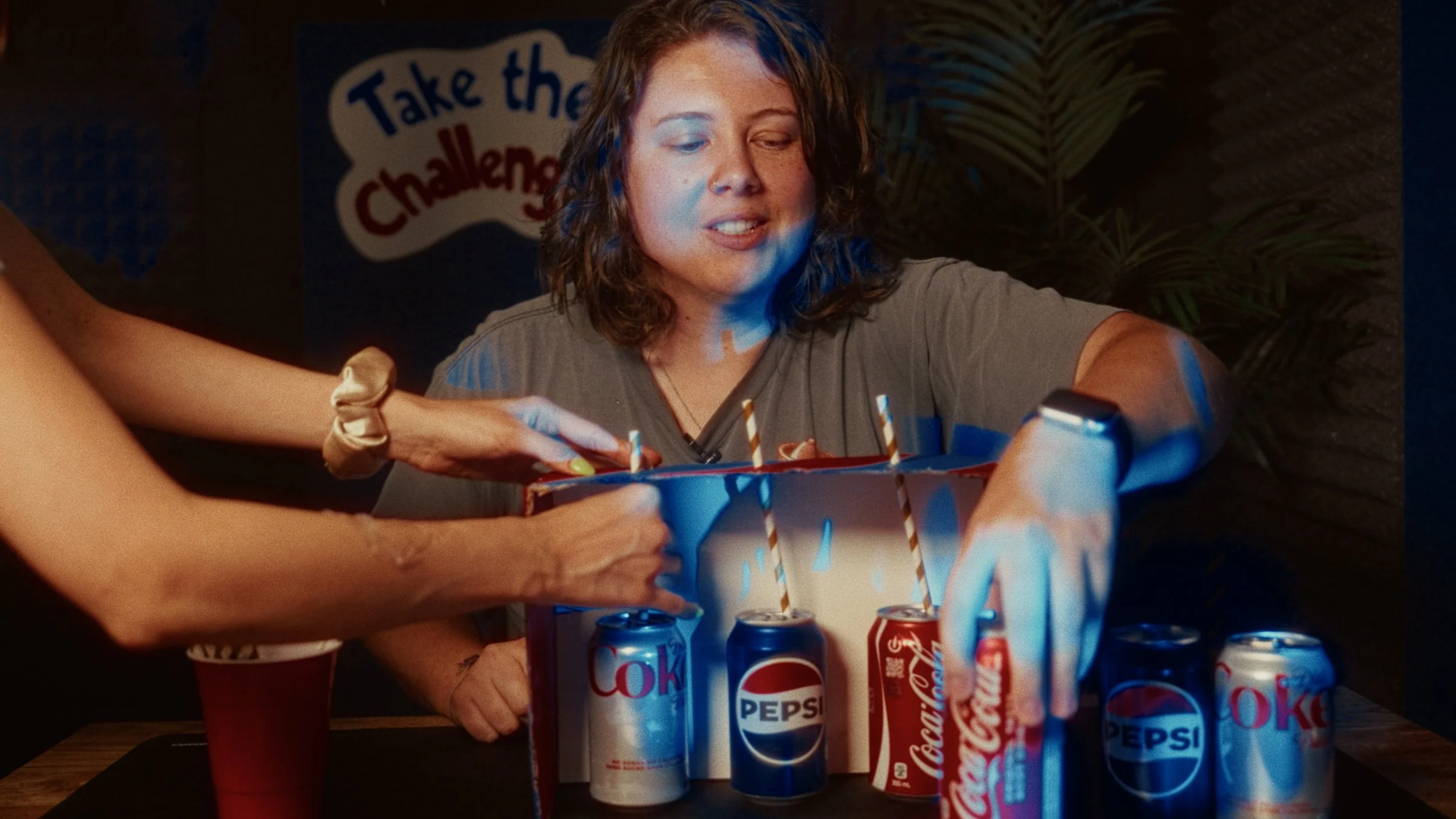 Woman opening a birthday cake with soda cans on a table, celebrating a birthday.