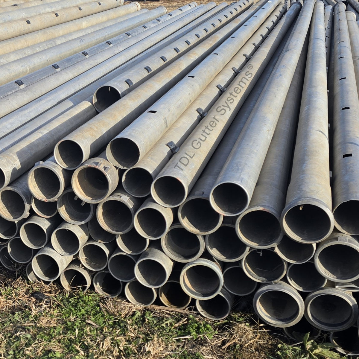 A stack of aluminum irrigation pipe on the ground.