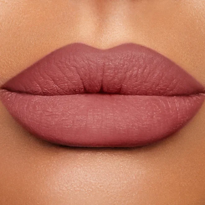 Close-up of full lips with nude lipstick, lips slightly parted.