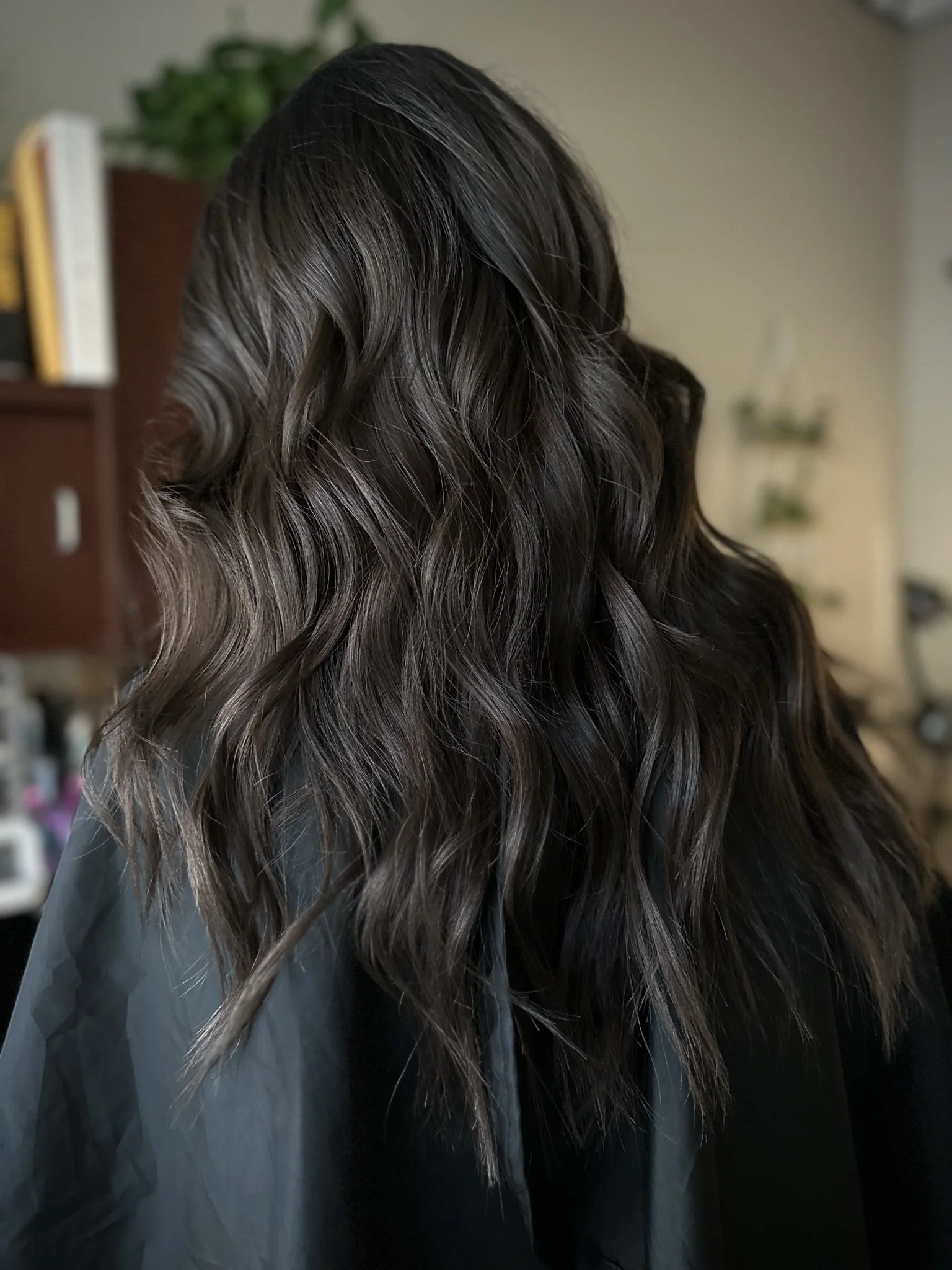 Glossy dark brunette hair featuring espresso and chocolate brown tones with soft waves by Leah Taylor Salon in St. Petersburg, Florida.