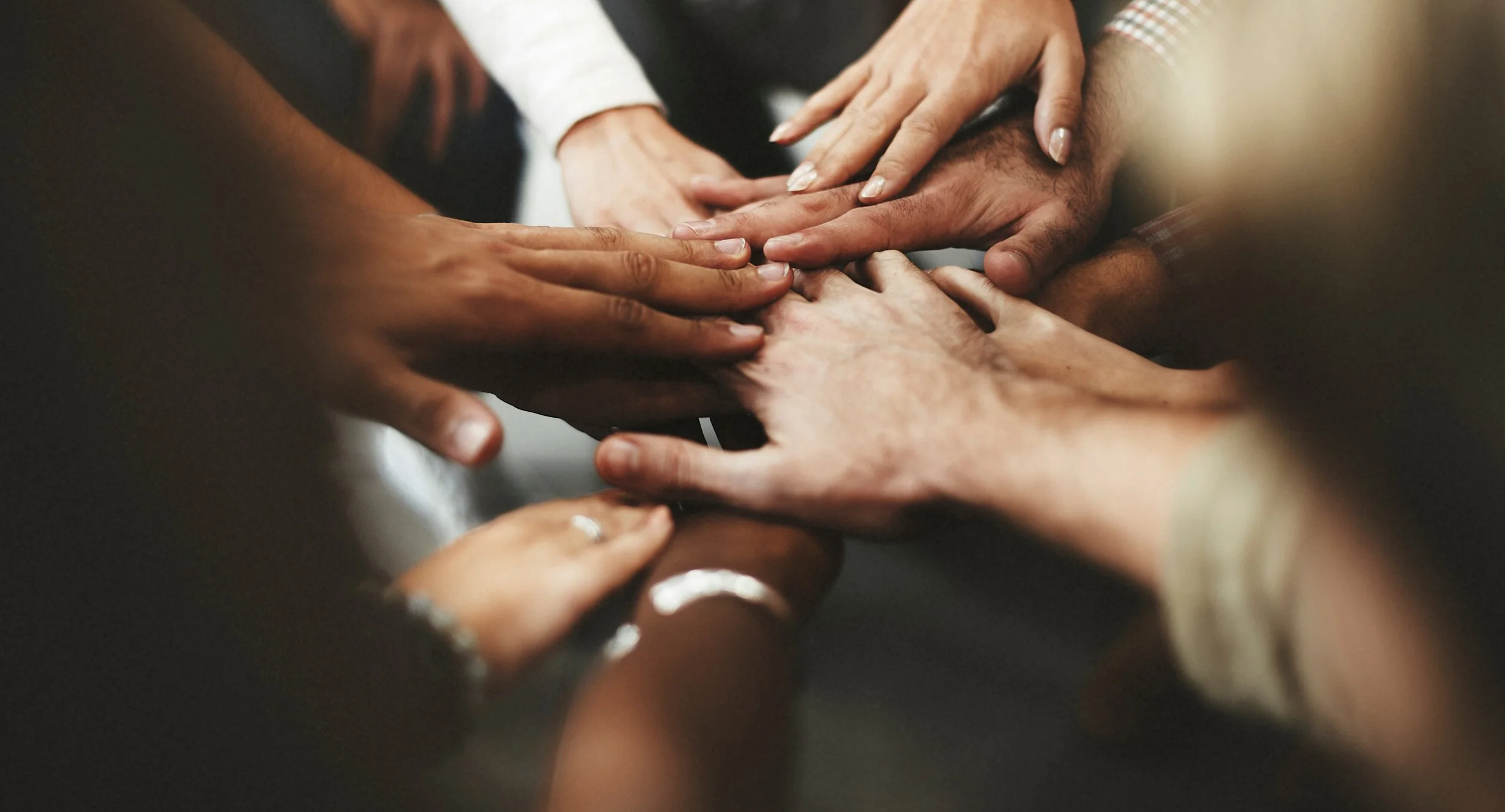 Group of diverse hands stacked together in a gesture of unity.