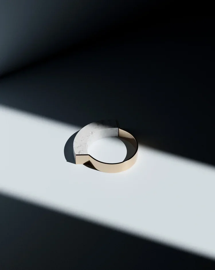 A circular metallic object with a modern design, placed on a surface with strong light and shadow effects.