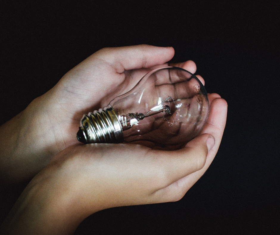 Two hands holding a broken incandescent light bulb