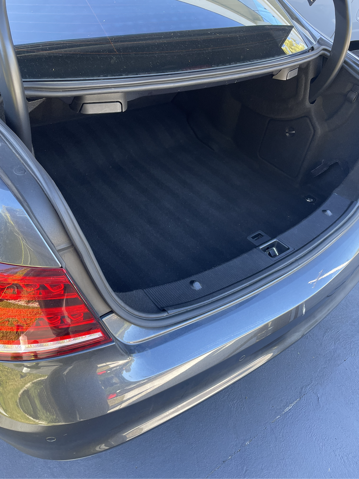 Open trunk of a silver car showing a clean interior with black carpeting.