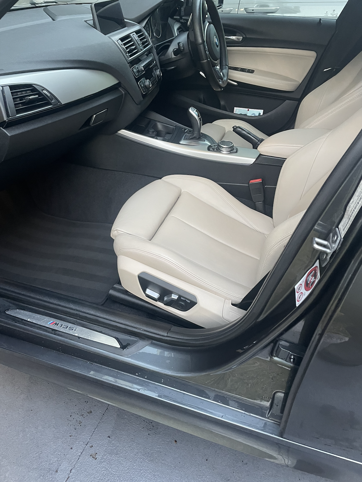 Interior of a BMW car with beige leather seats, black dashboard, and center console featuring a gear shifter and control knobs.