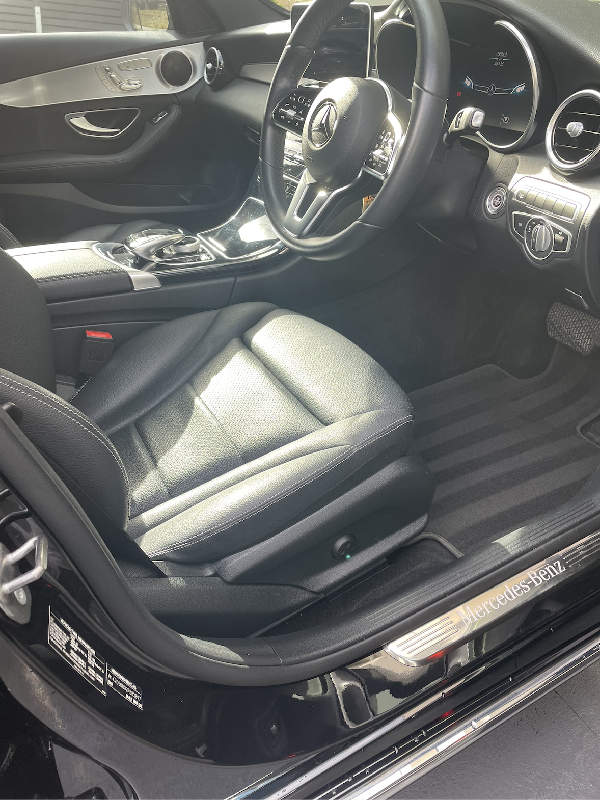 Interior of a Mercedes-Benz car showing the driver's seat, steering wheel, dashboard, and part of the center console.