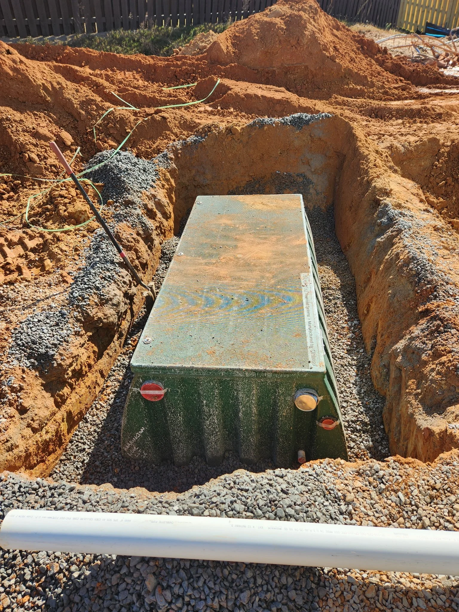 Underground utility box install in gravel surrounded by soil trenches, with electrical wires nearby.