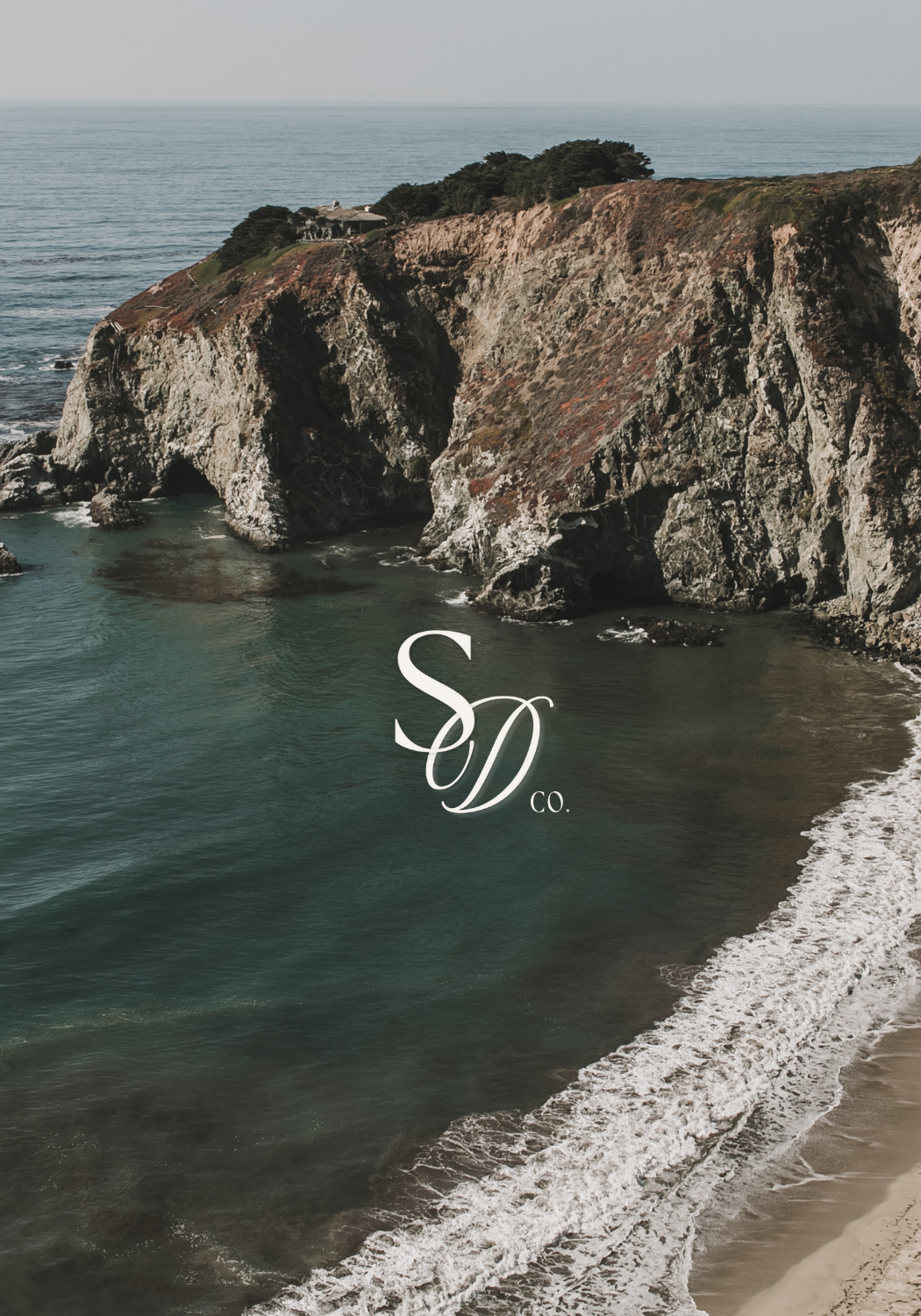 Coastal cliffs overlooking the ocean with waves hitting the shore and trees on top, with the text 'SD Co.' in the center.