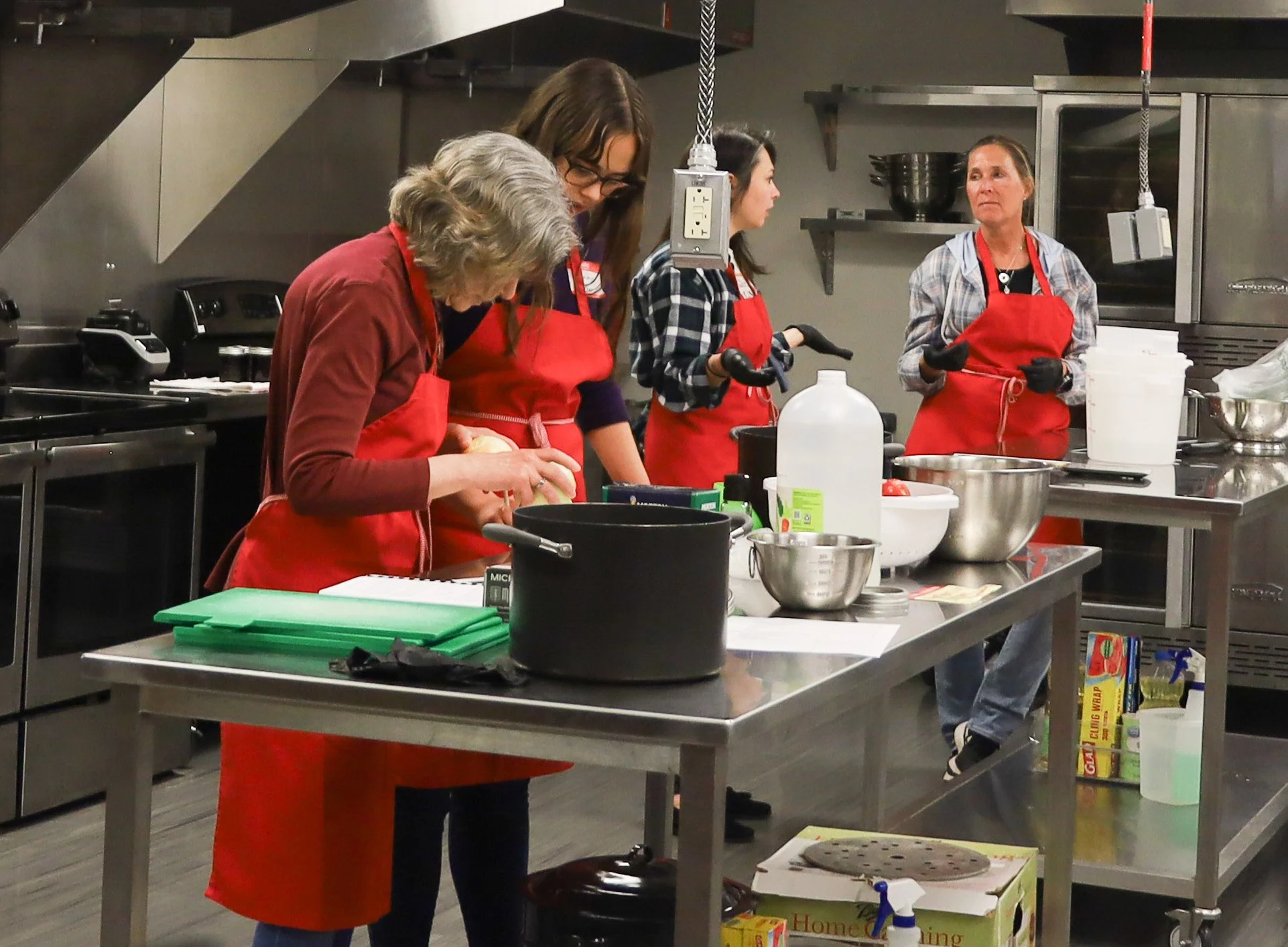 Students in red aprons learning to preserve foods in a CSU kitchen