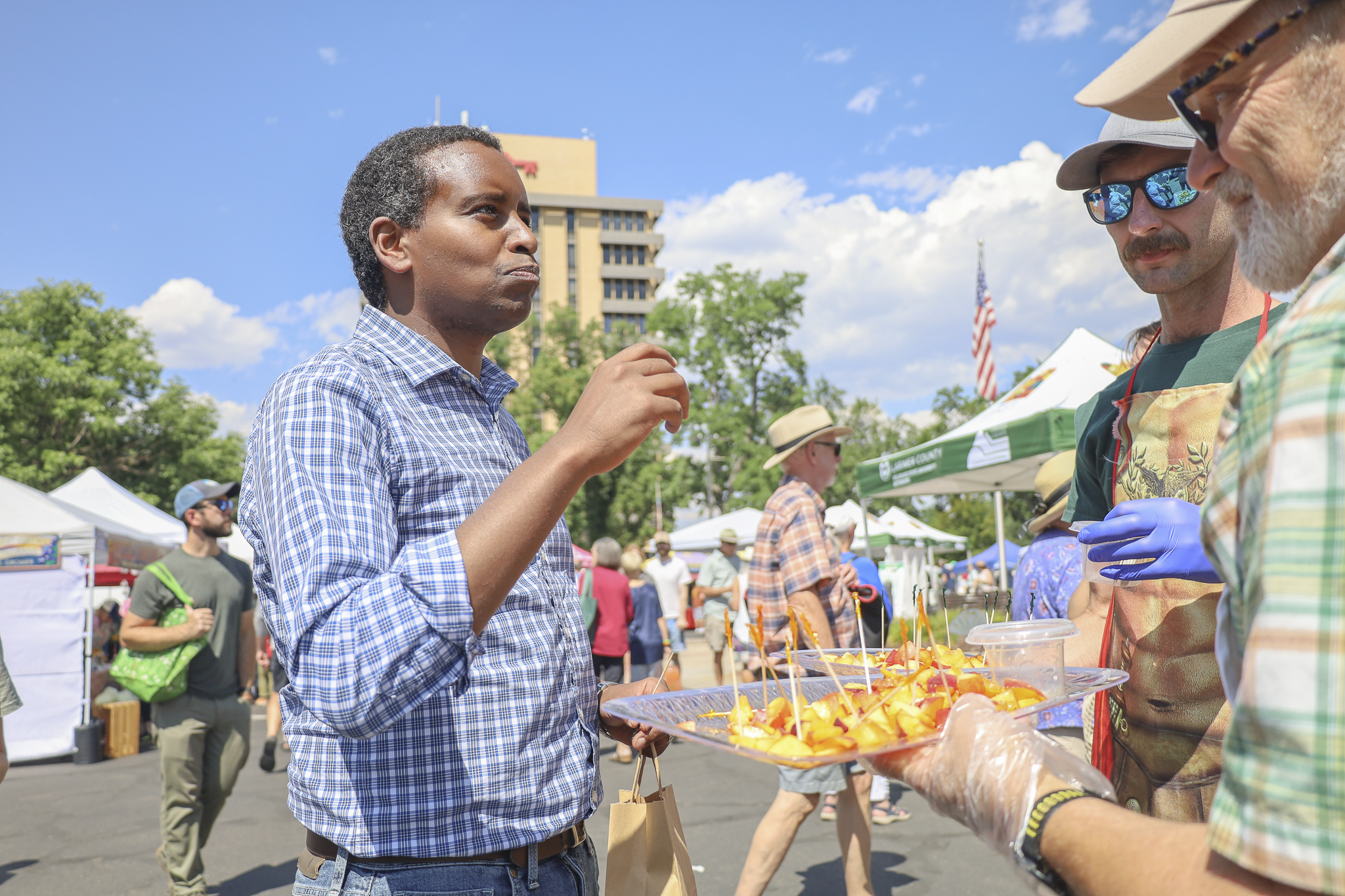 Man tastes peach samples at the Farmers' Market