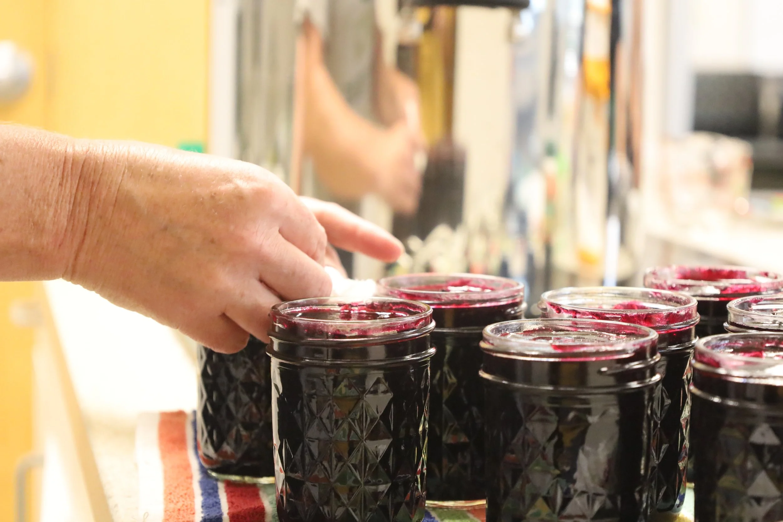 Person filling cans of preserves 