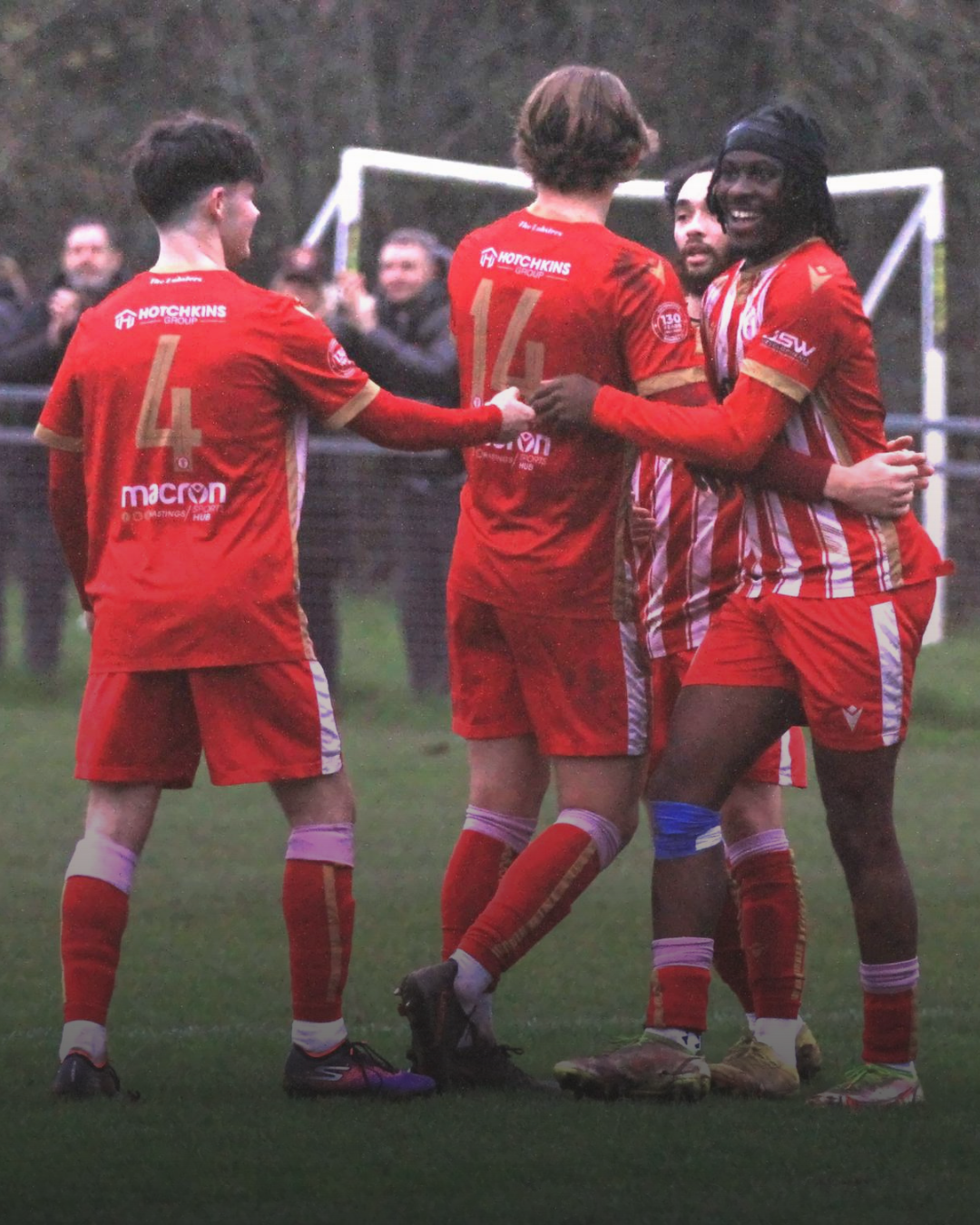 Soccer players in red and white uniforms celebrating on the field.