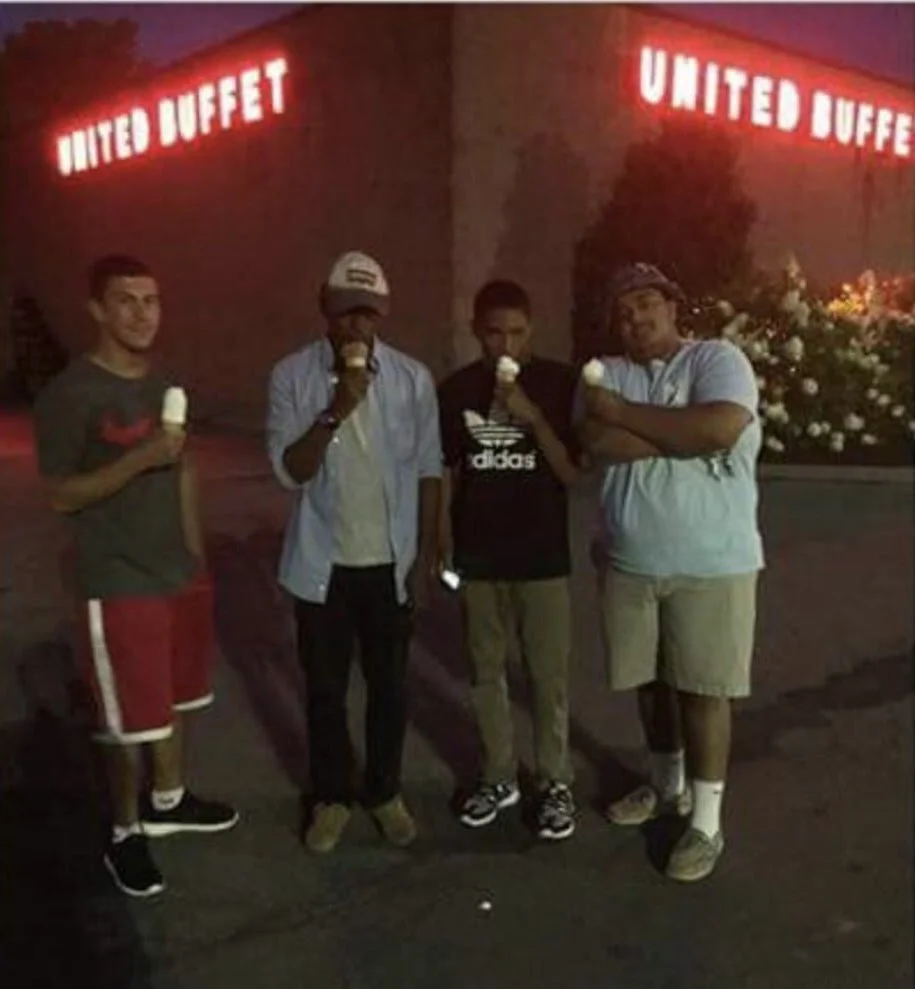 Four young men standing outside at night near the United Buffet restaurant, each holding a cup of ice cream.