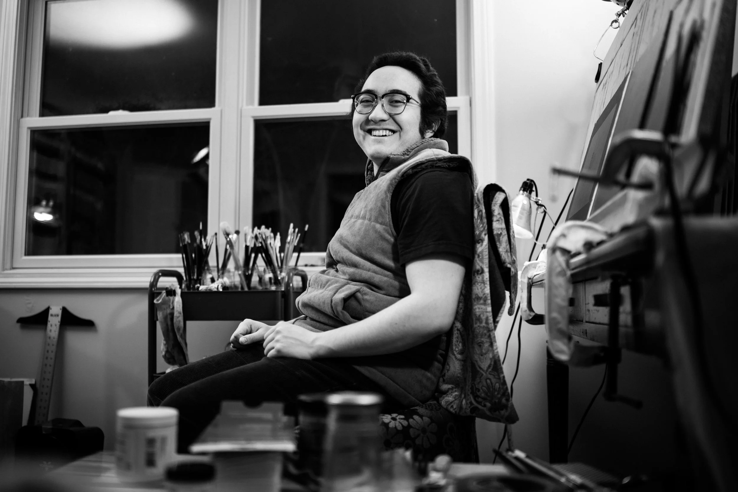 Alex Blazar Paternostro sits in his painting studio in a black and white portrait photograph taken by his identical twin brother, Seth Paternostro.