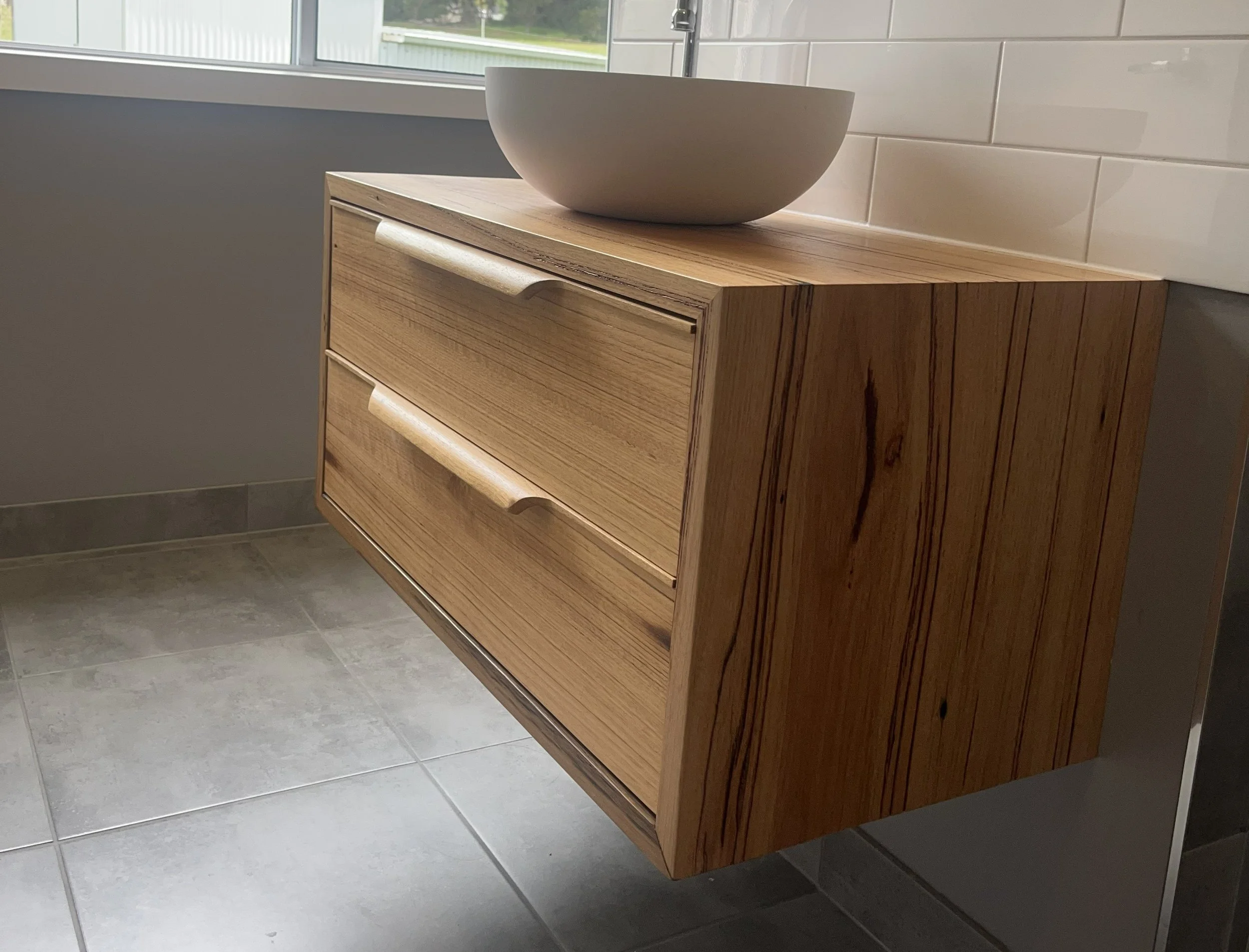 Wooden bathroom vanity with two drawers, mounted on the wall, with a white bowl on top.