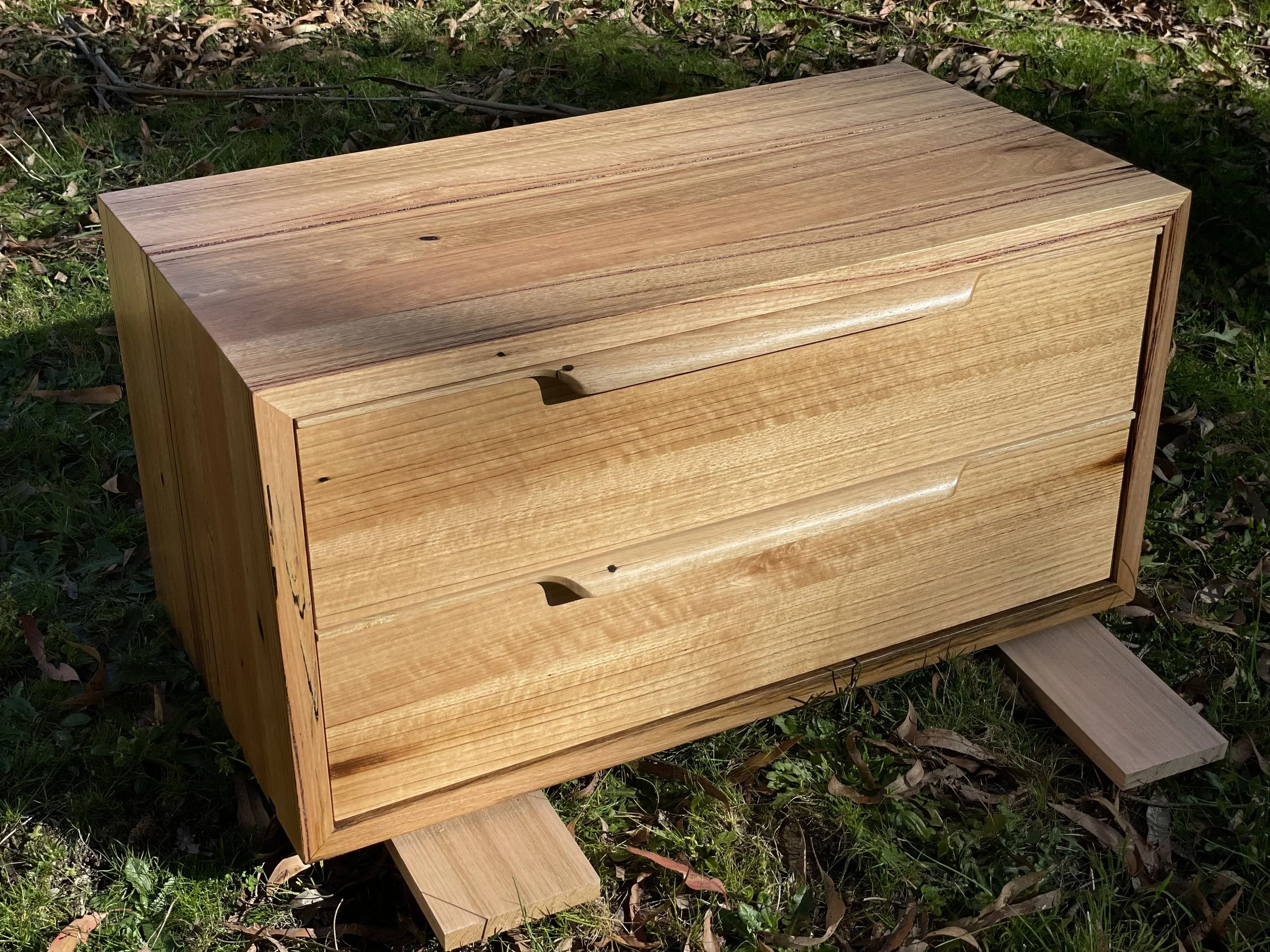 A wooden chest with two drawers on a grassy ground.