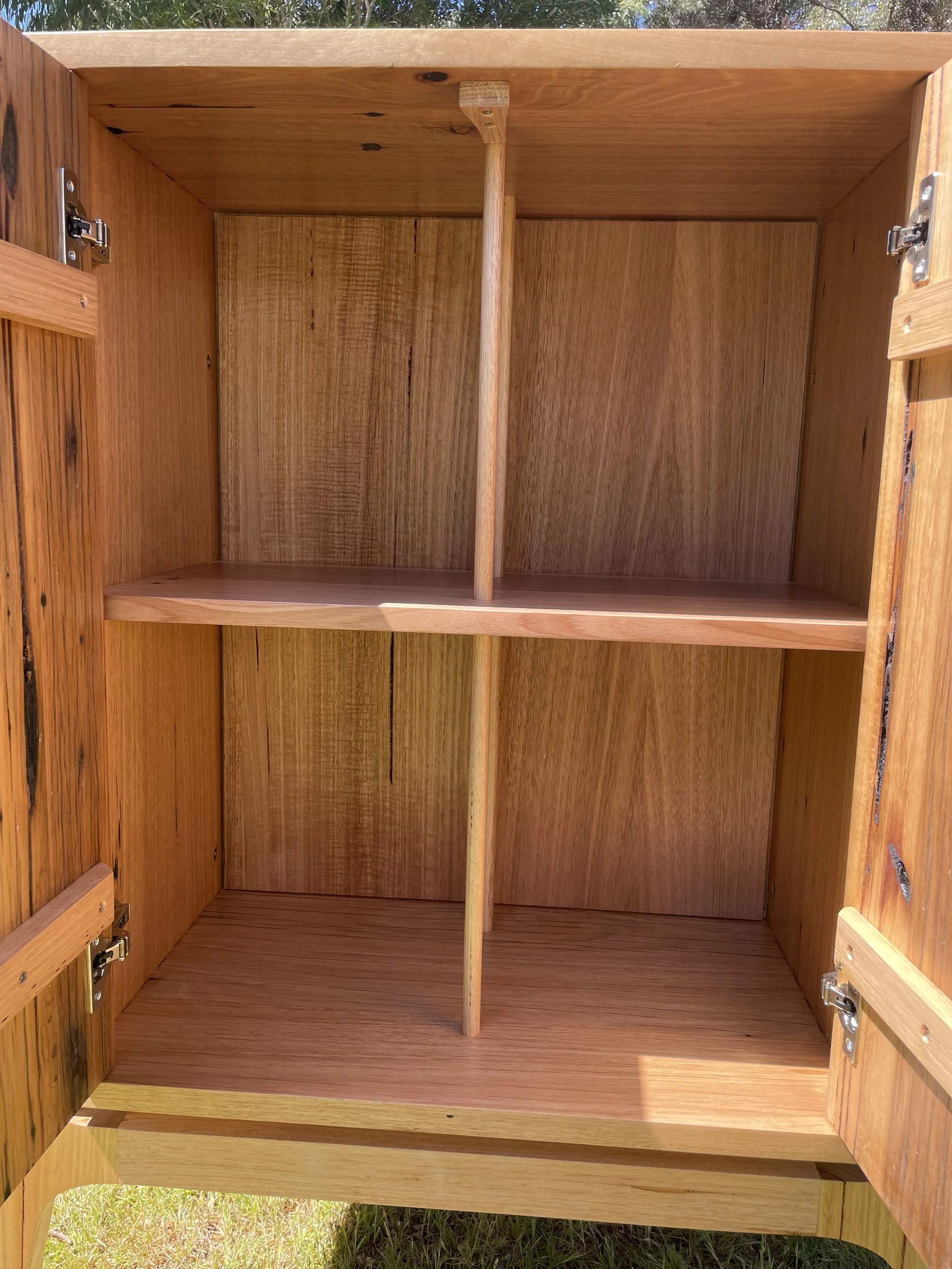 Empty wooden outdoor cabinet with three shelves inside and open doors.