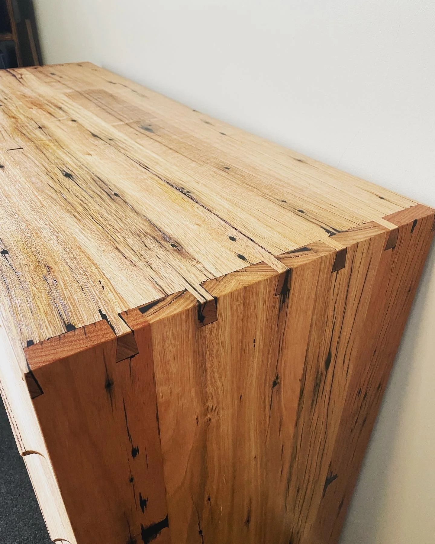 Close-up of a wooden furniture piece with visible wood grain and dovetail joints.