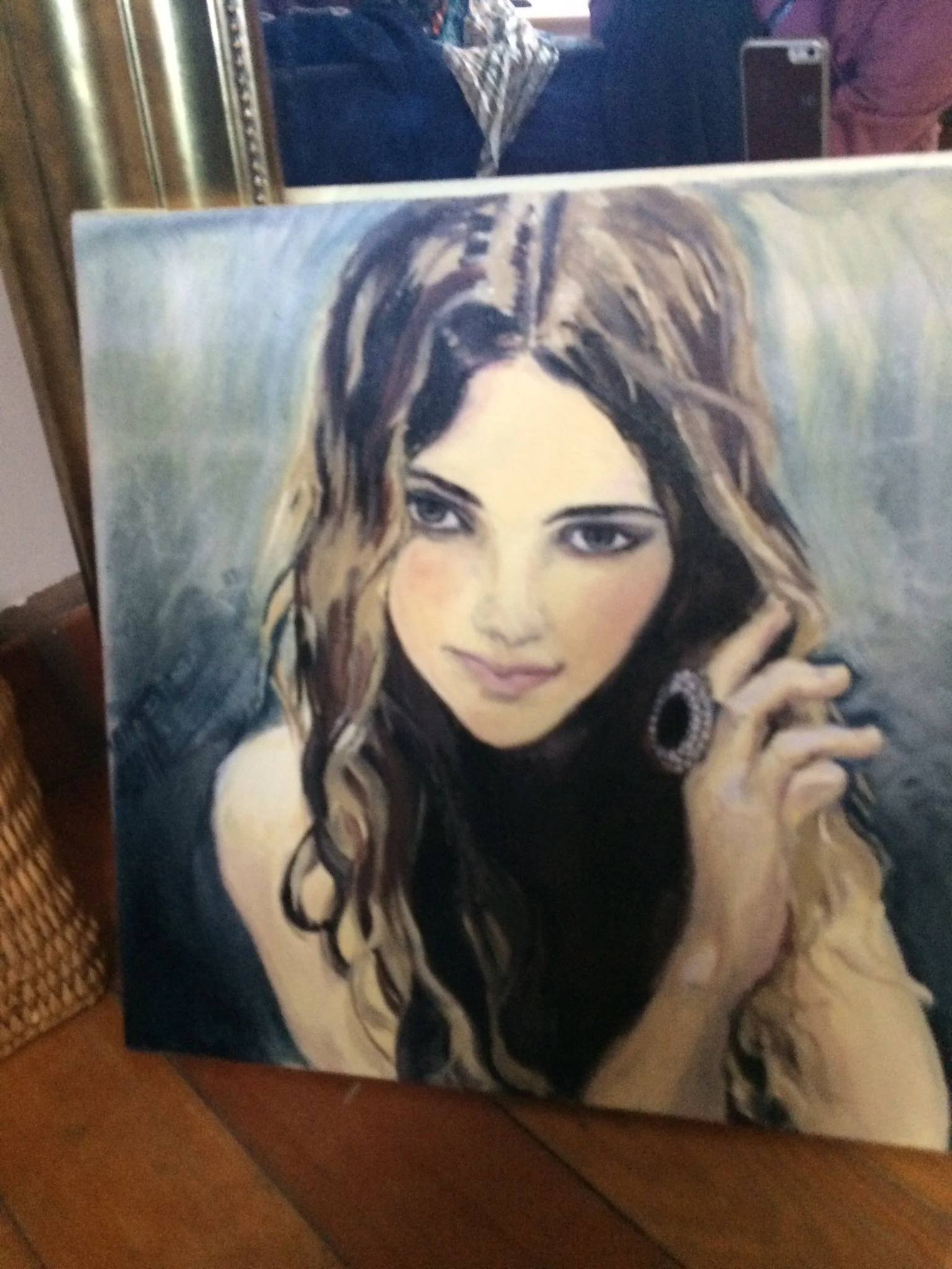 Painting of a woman with wavy brown hair, wearing a black top and large circular earrings, holding her hand near her face.