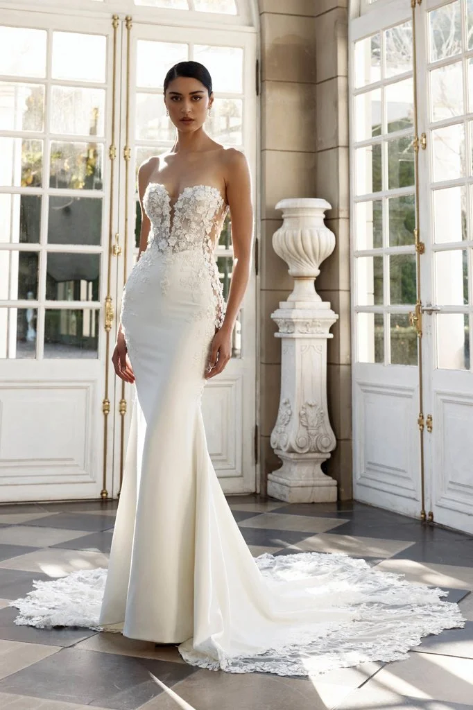 Shop Denver by Jeune at Bride To Be Couture in Sacramento, California. This fitted lace wedding dress features illusion long sleeves, floral appliqués, and a romantic sculpted silhouette.