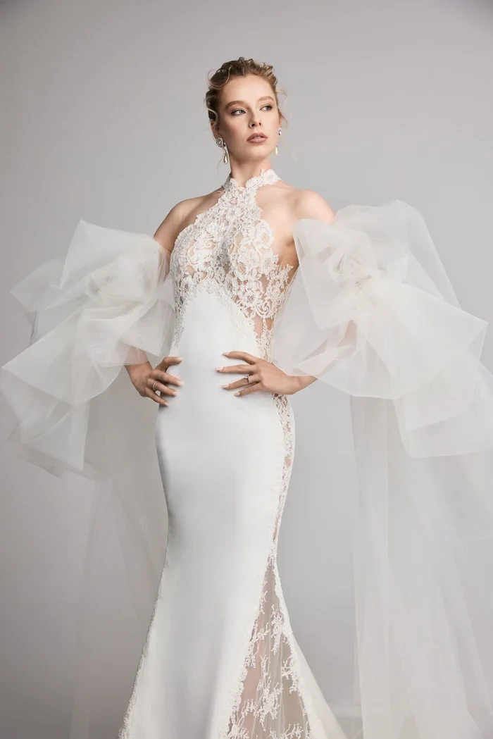 Halter neckline sheath with accentuated godet in back. Paired with opulent flowing sleeves.