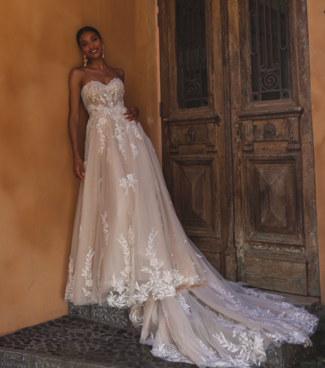 Madi Lane Pandora ballgown wedding dress with a strapless illusion bodice, motif lace adorned with sequins and beads, and a grand full-circle skirt and illusion train.
