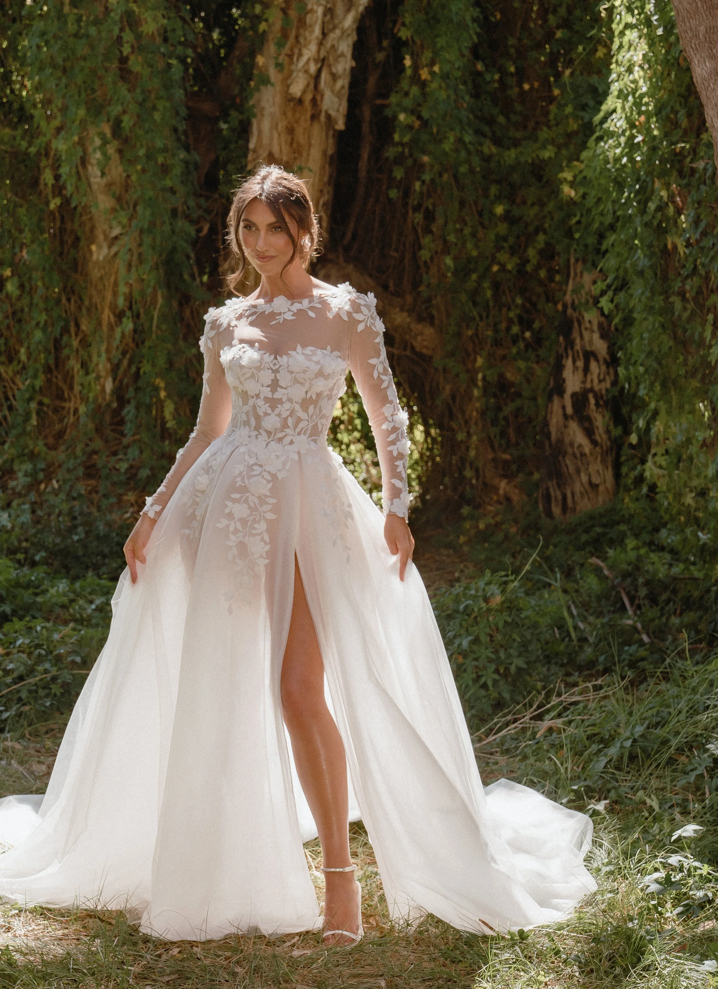 Madi Lane Samara strapless A-line wedding gown with an illusion bodice, 3D floral lace, dramatic tulle skirt, and detachable long-sleeve illusion topper.