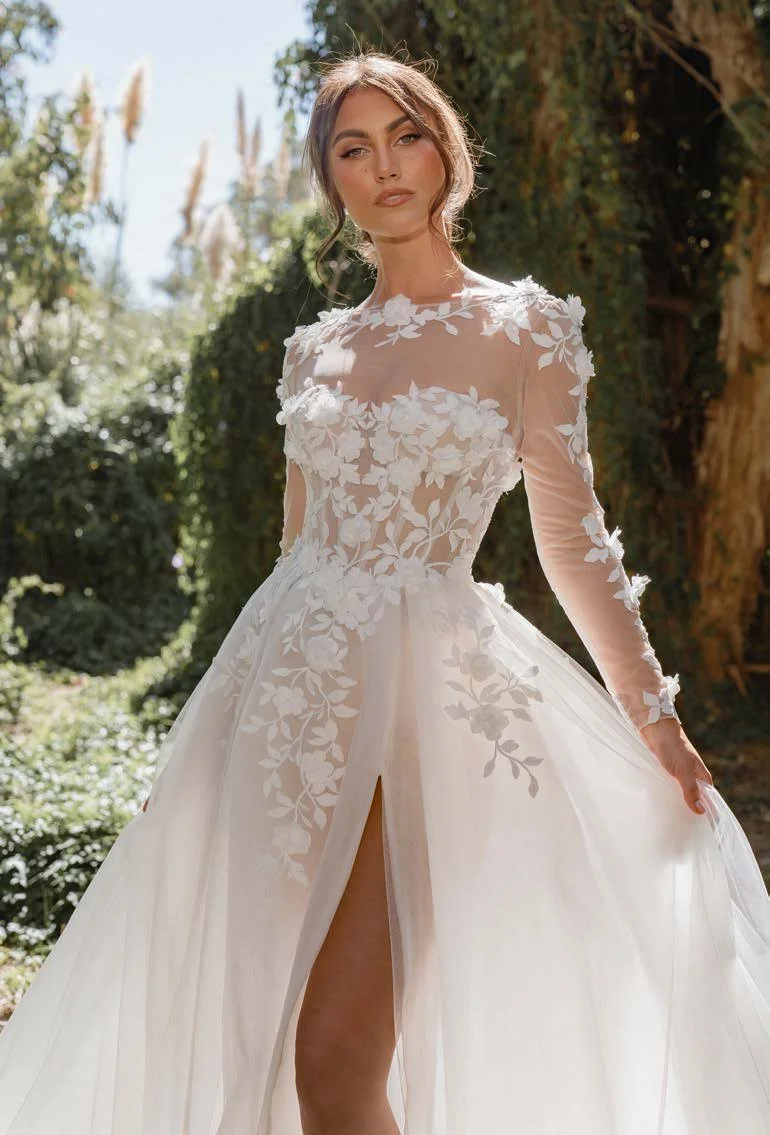 Madi Lane Samara strapless A-line wedding gown with an illusion bodice, 3D floral lace, dramatic tulle skirt, and detachable long-sleeve illusion topper.