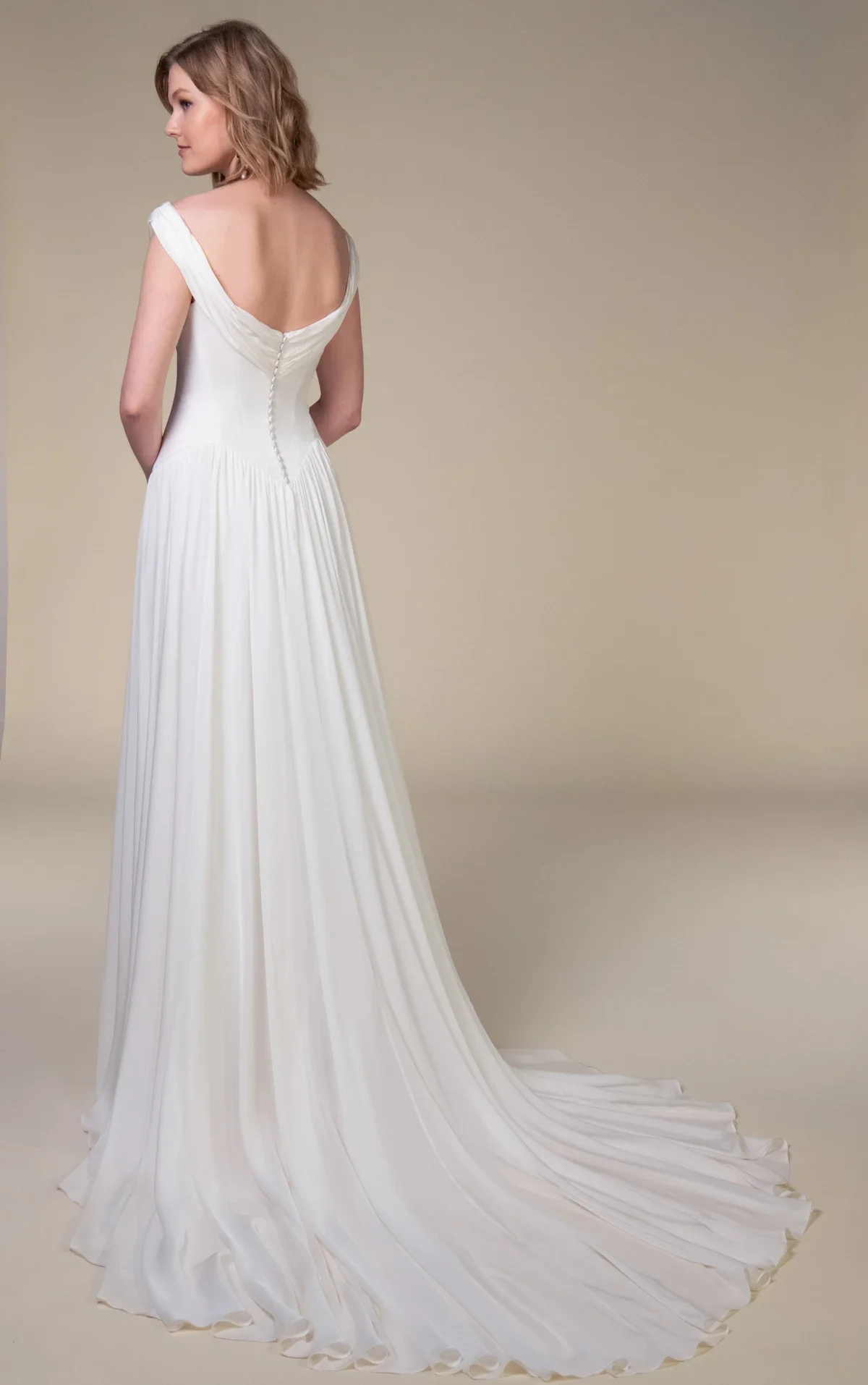 All Who Wander Cosete off-the-shoulder A-line wedding dress in silk double georgette with draped wrap bodice, dropped basque waist, and low V-back, available at Bride To Be Couture in Sacramento
