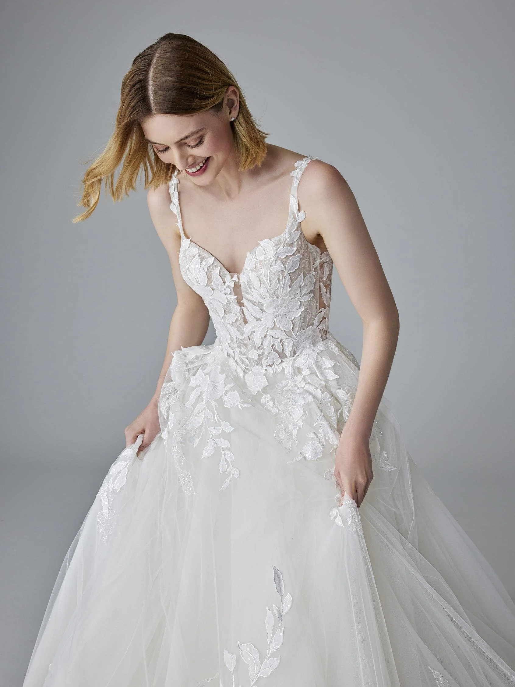 Pronovias Kamerie lace-and-tulle ball gown wedding dress with a sweetheart bodice, sheer rhinestone straps, glitter lace, and voluminous tulle skirt.