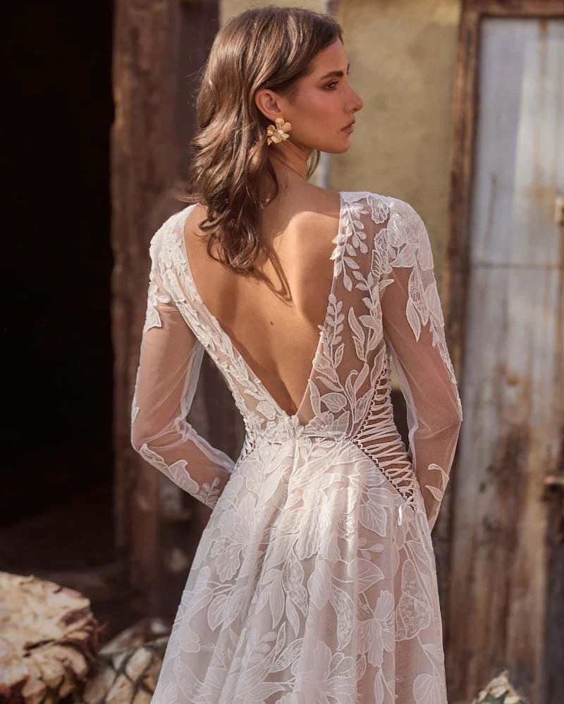 La Perle Gayle boho lace A-line wedding dress with high jewel illusion neckline, long lace sleeves, side cutouts, and low back.