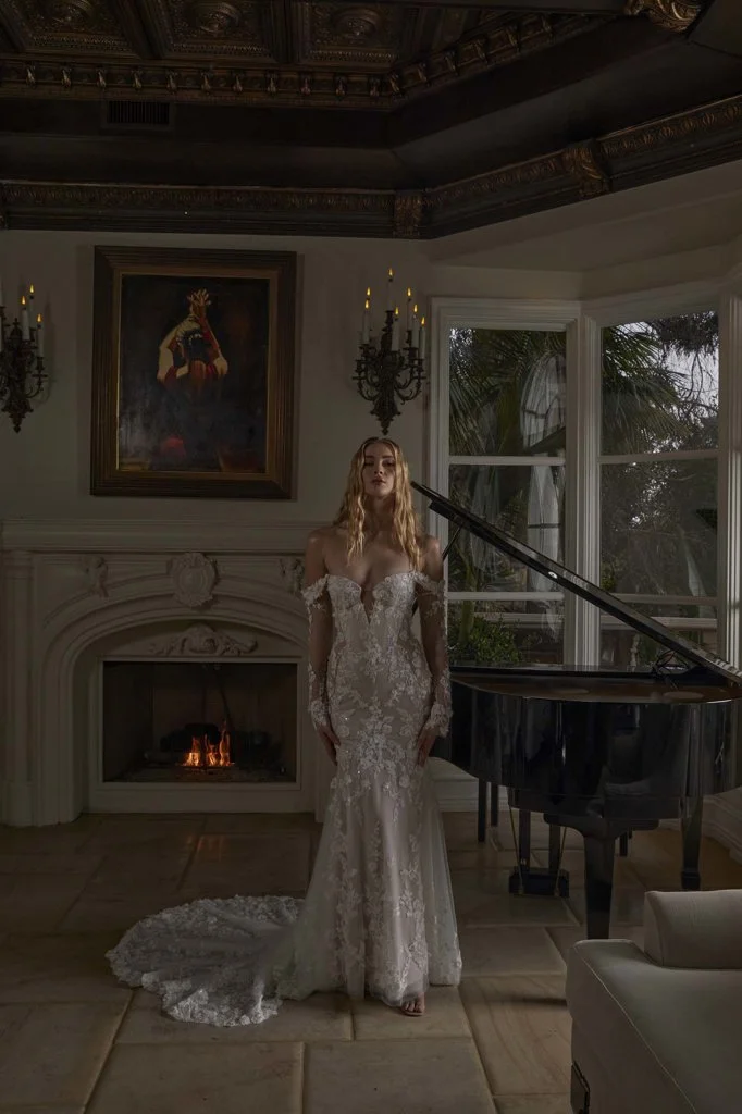 Serene Ame Raquel fit-and-flare wedding dress with 3D lace over soft tulle, sweetheart bustier, sheer sides, illusion train, and detachable off-shoulder sleeves.