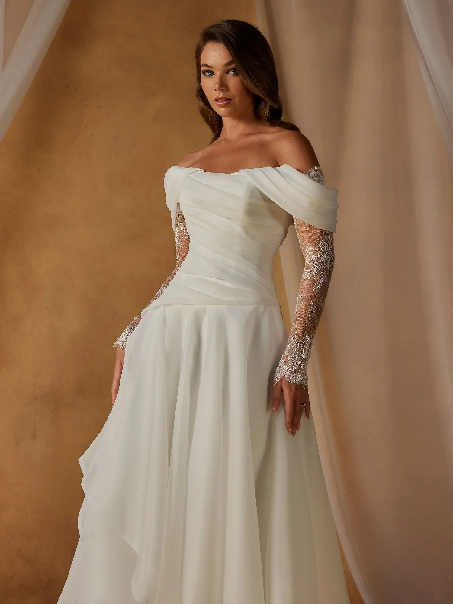 Madi Lane Nettle A-line organza wedding dress with three styling options — strapless, off-shoulder sleeves, or lace illusion sleeves — plus drop-waist pleating and pearl-trimmed train.