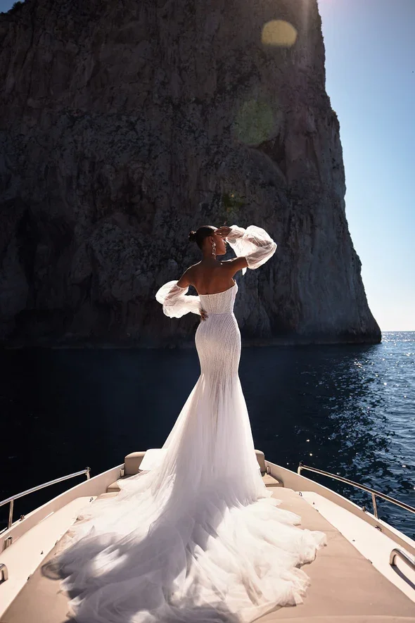 Julie Vino Marissa fit-and-flare wedding gown with a strapless sweetheart cat-eye neckline, off-the-shoulder long puff sleeves, and beaded lace over tulle.