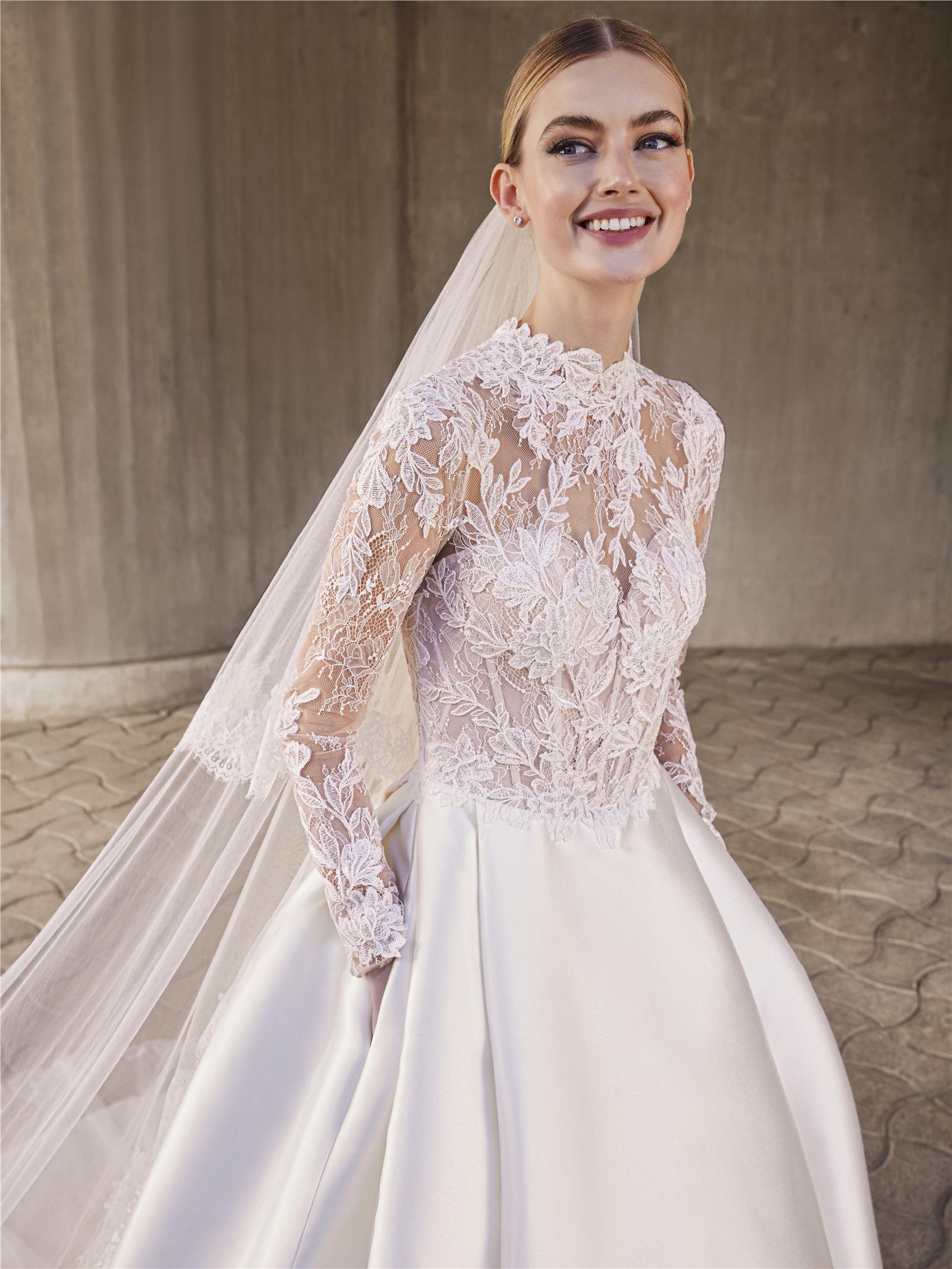 Pronovias Maplis princess ball gown with a high-neck lace bodice, long sleeves, Chantilly and corded lace detailing, and a Mikado skirt.