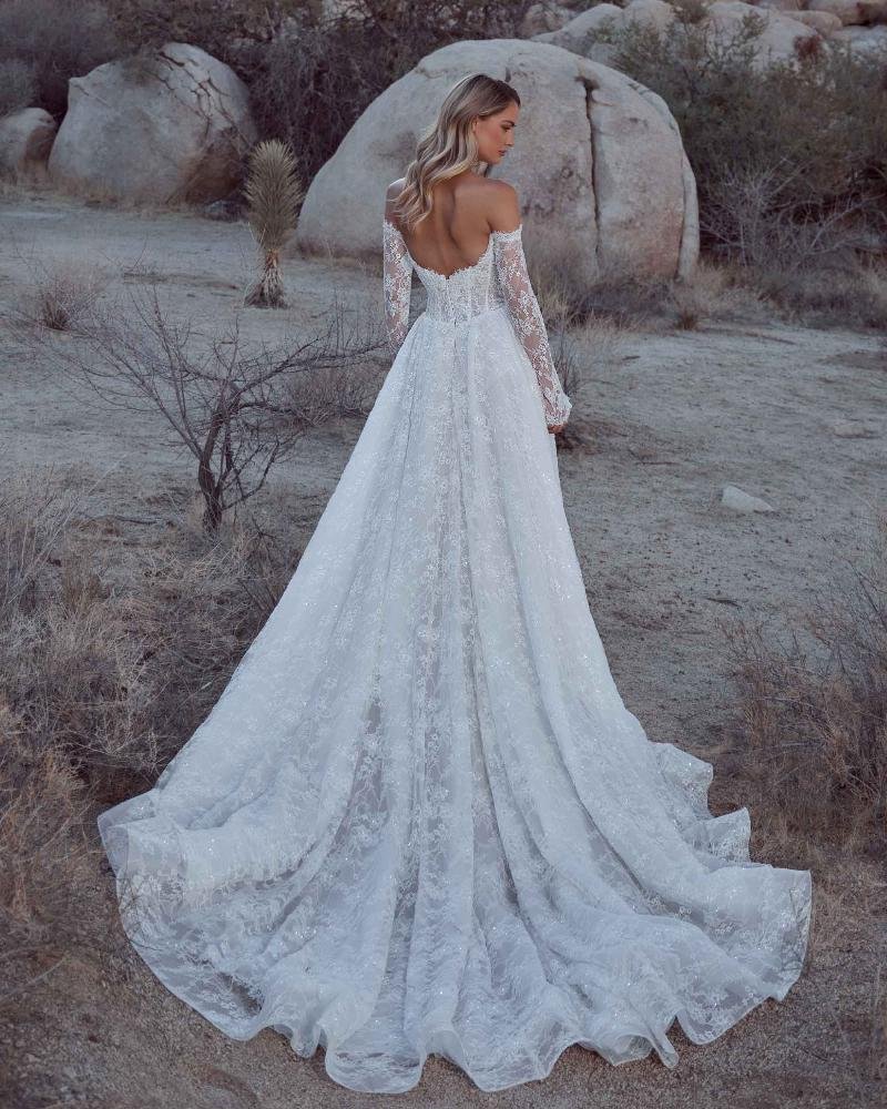 Calla Blanche Bianca 126105 sparkly basque waist A-line wedding dress with strapless sweetheart neckline, cascading lace, detachable long sleeves, and detachable beaded bodice accessory.