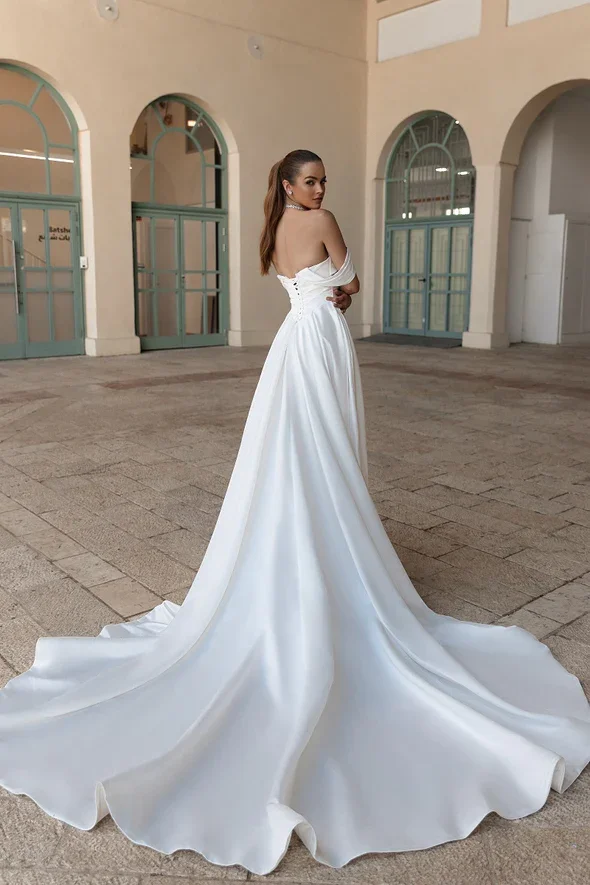Julie Vino Grace satin A-line wedding gown with a strapless sweetheart cat-eye neckline, off-the-shoulder draping, body ruching, and a defined Basque waist.