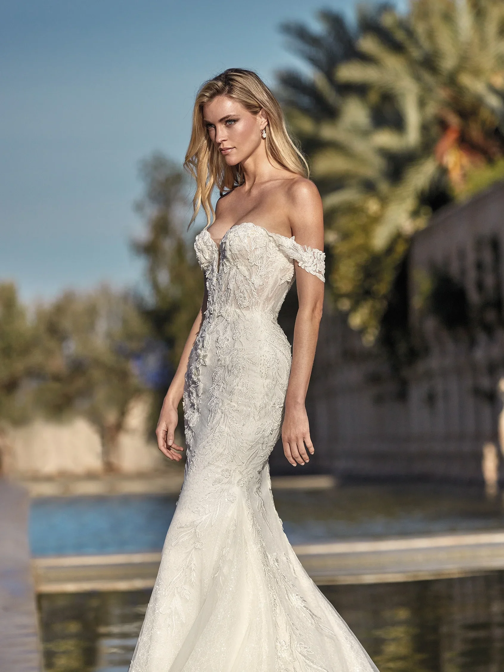 Pronovias Kenai glitter mermaid wedding dress with an off-the-shoulder neckline and sculpted figure-hugging silhouette.