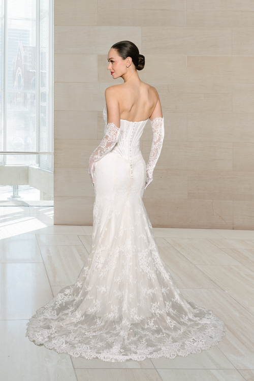Elizabeth Lee Audrey fit-and-flare Italian lace gown with an unlined corset bodice, asymmetrical pleated sash, and matching lace gloves, available at Bride To Be Couture in Sacramento.