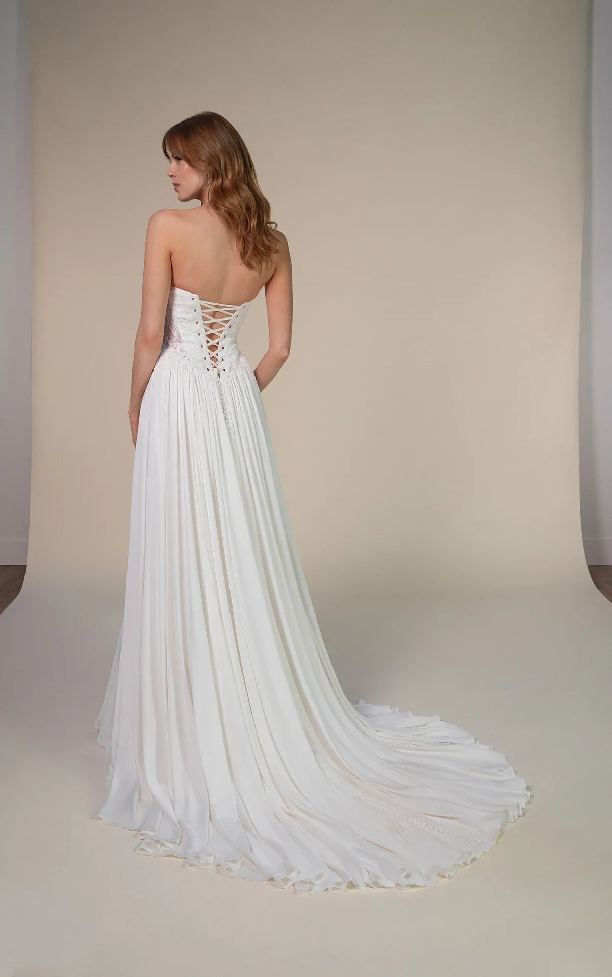 All Who Wander Romin strapless boho wedding dress in silk double crepe and lace with cat-eye neckline, side cutouts, and gathered chiffon hips, available at Bride To Be Couture in Sacramento.
