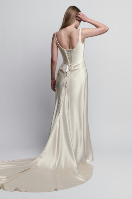 Polished charmeuse sheath wedding dress with a draped bodice, exposed corsetry, lace-up back, and straps..