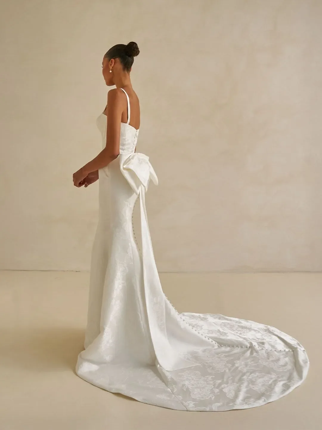 Madi Lane Walsh floral jacquard sheath wedding gown with a square neckline, detachable straps, and an included A-line overskirt for two distinct looks.