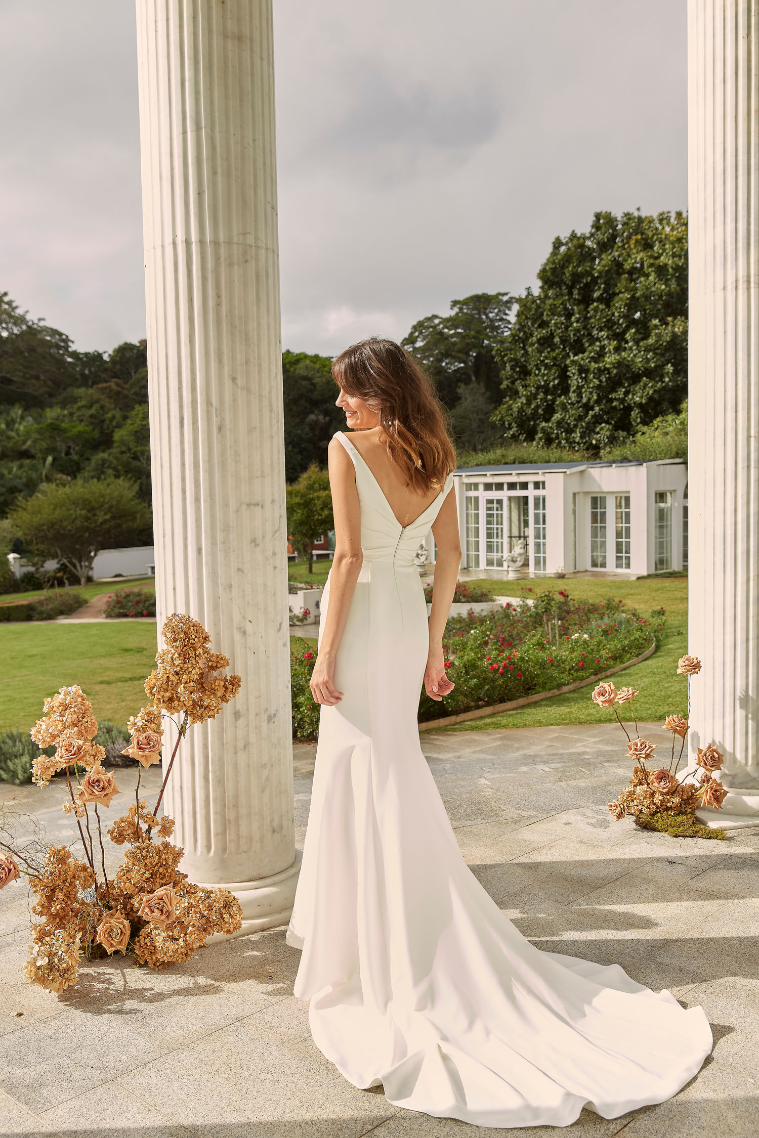 Madi Lane Darnelle minimalist crepe wedding dress with a body-hugging fit, dramatic leg split, and timeless sweeping train.