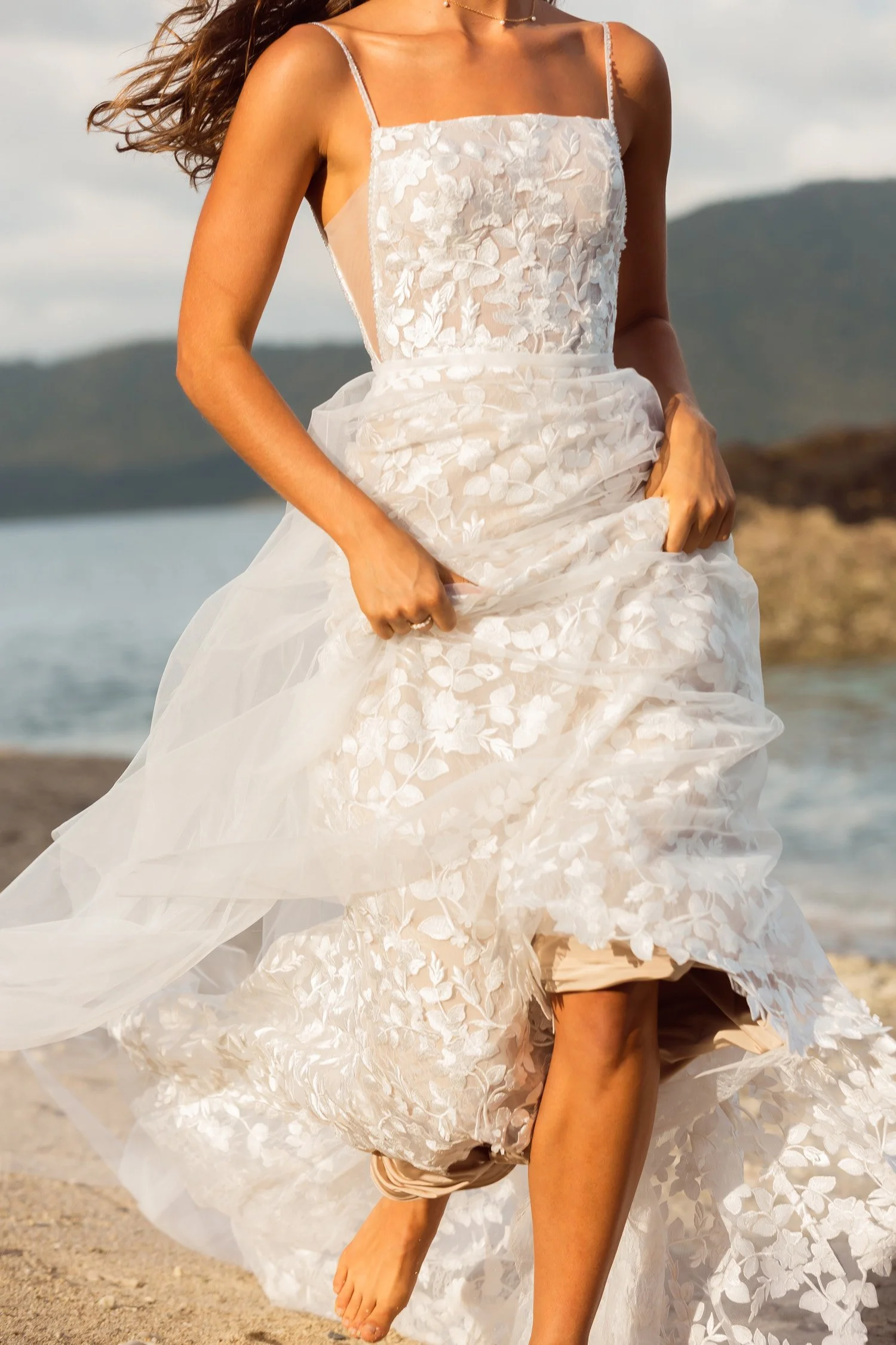 Madi Lane Jovi fitted sheath wedding dress with a square illusion neckline, side cutouts, all-over floral lace, and a detachable tulle overskirt.