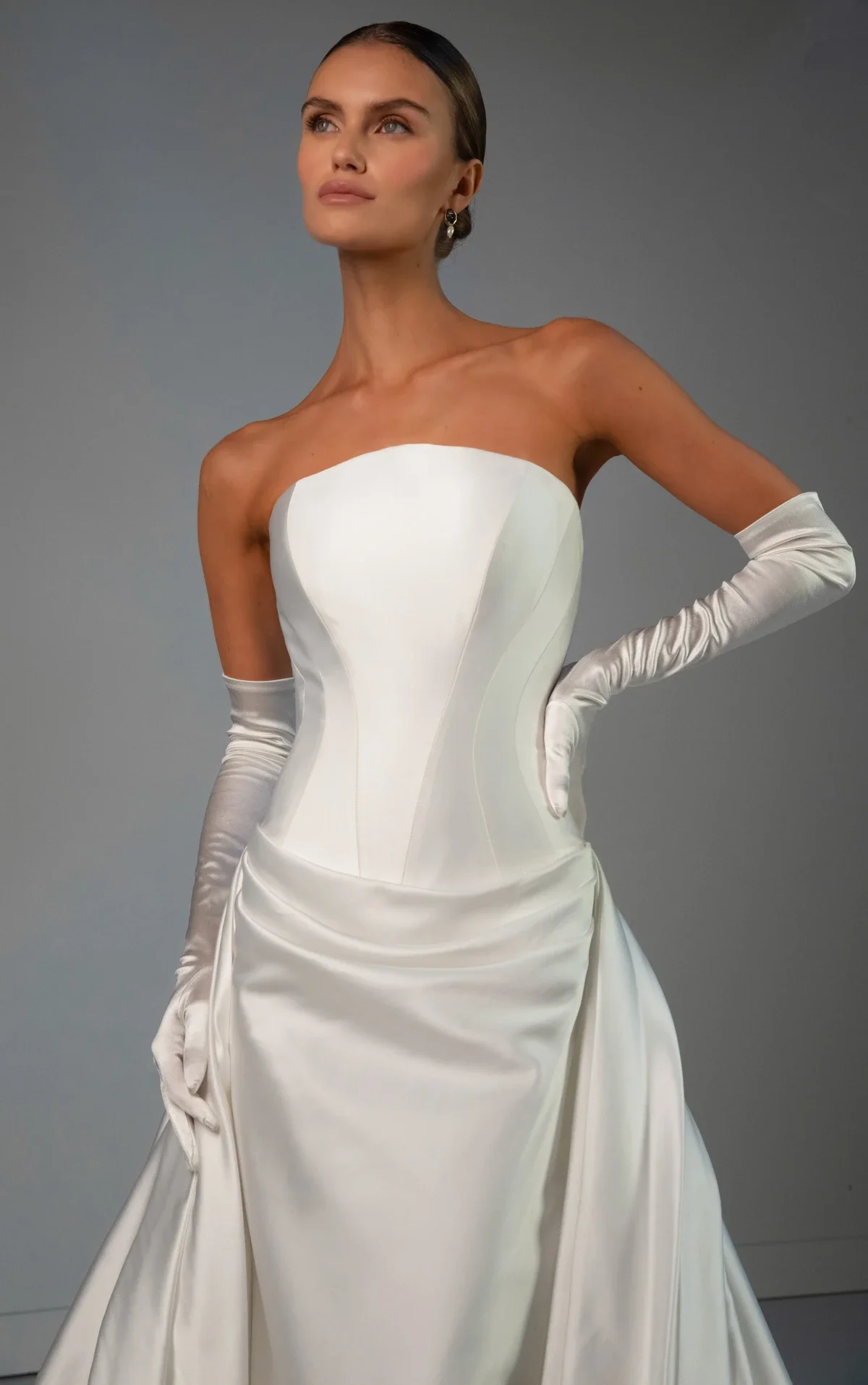 Martina Liana Luxe LE1460 strapless satin wedding dress with corset bodice, column silhouette, dramatic overskirt, and opera gloves at Bride To Be Couture Sacramento